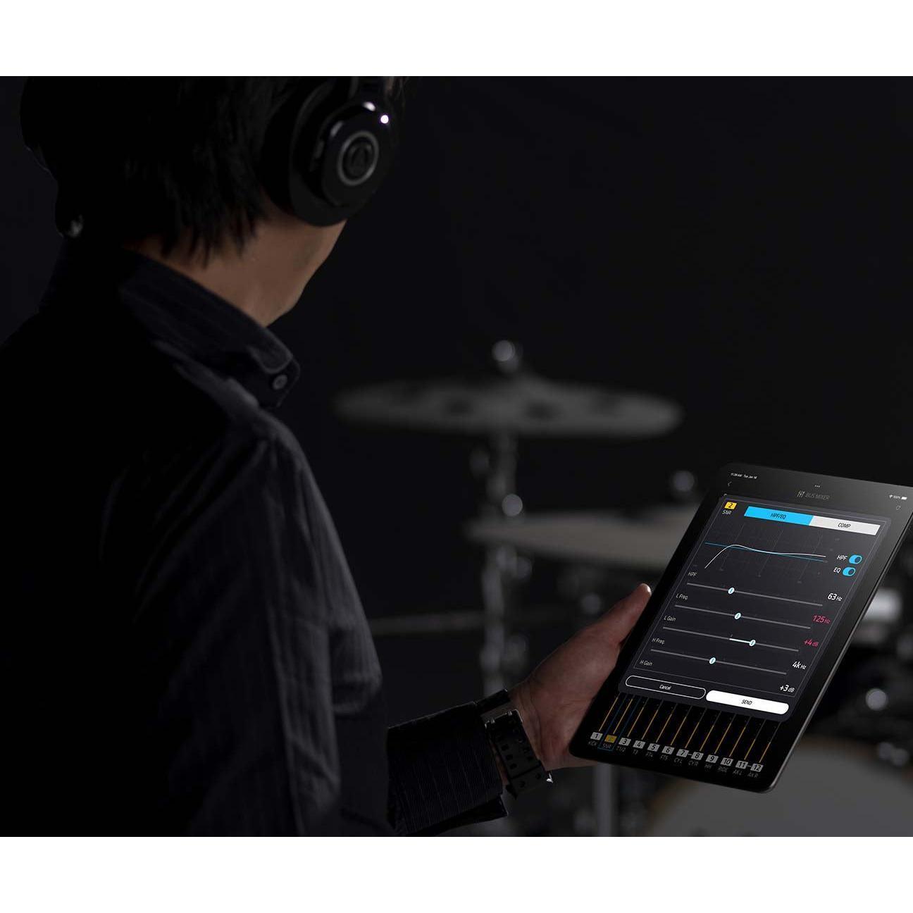 Person wearing headphones holding tablet with audio mixing app near EFNOTE PRO 703X electronic drum kit