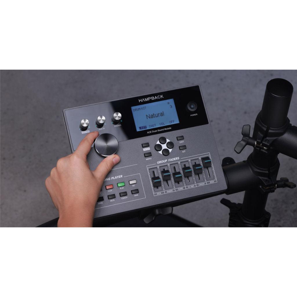 Close-up of a person adjusting controls on the Hampback ACE-360 e-drum set module with LCD display and faders