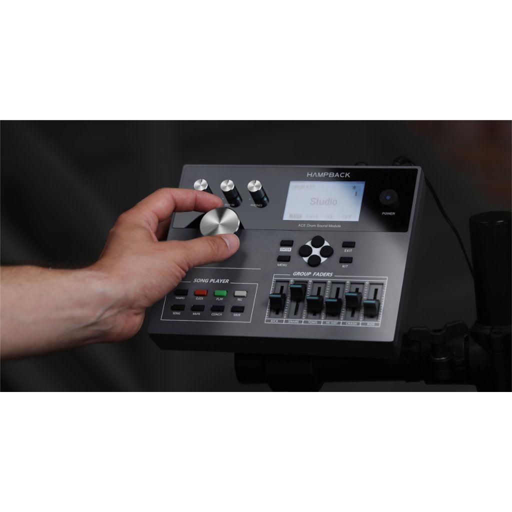 Close-up of hand adjusting control knob on the Hampback ACE-530 e-drum set sound module with faders and display.