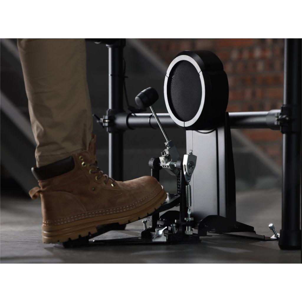 Close-up of a boot pressing the kick drum pedal on the Hampback ACE-530 e-drum set in a practice setting.