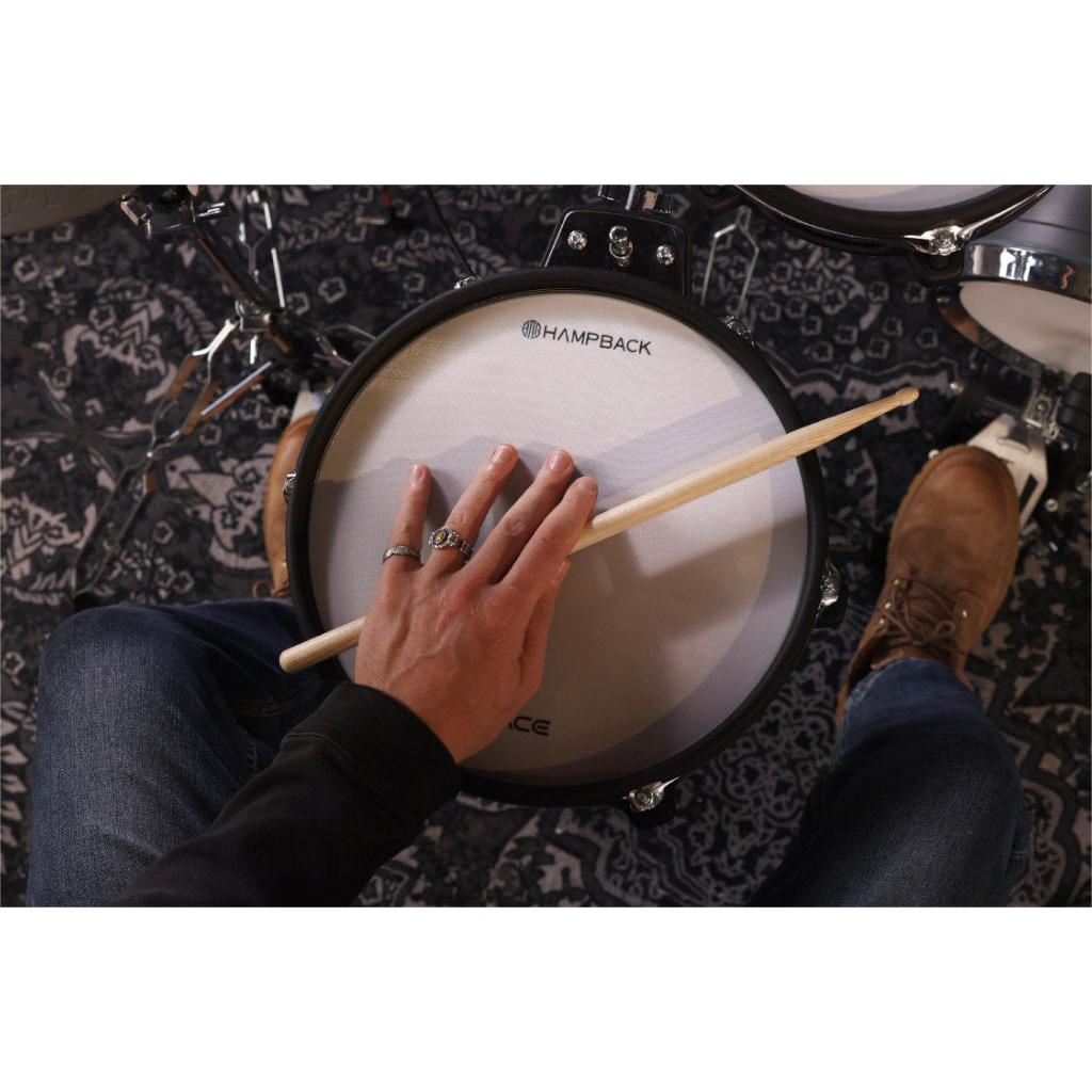 Close-up of a person playing the Hampback ACE-970 e-drum set snare drum with a wooden drumstick.