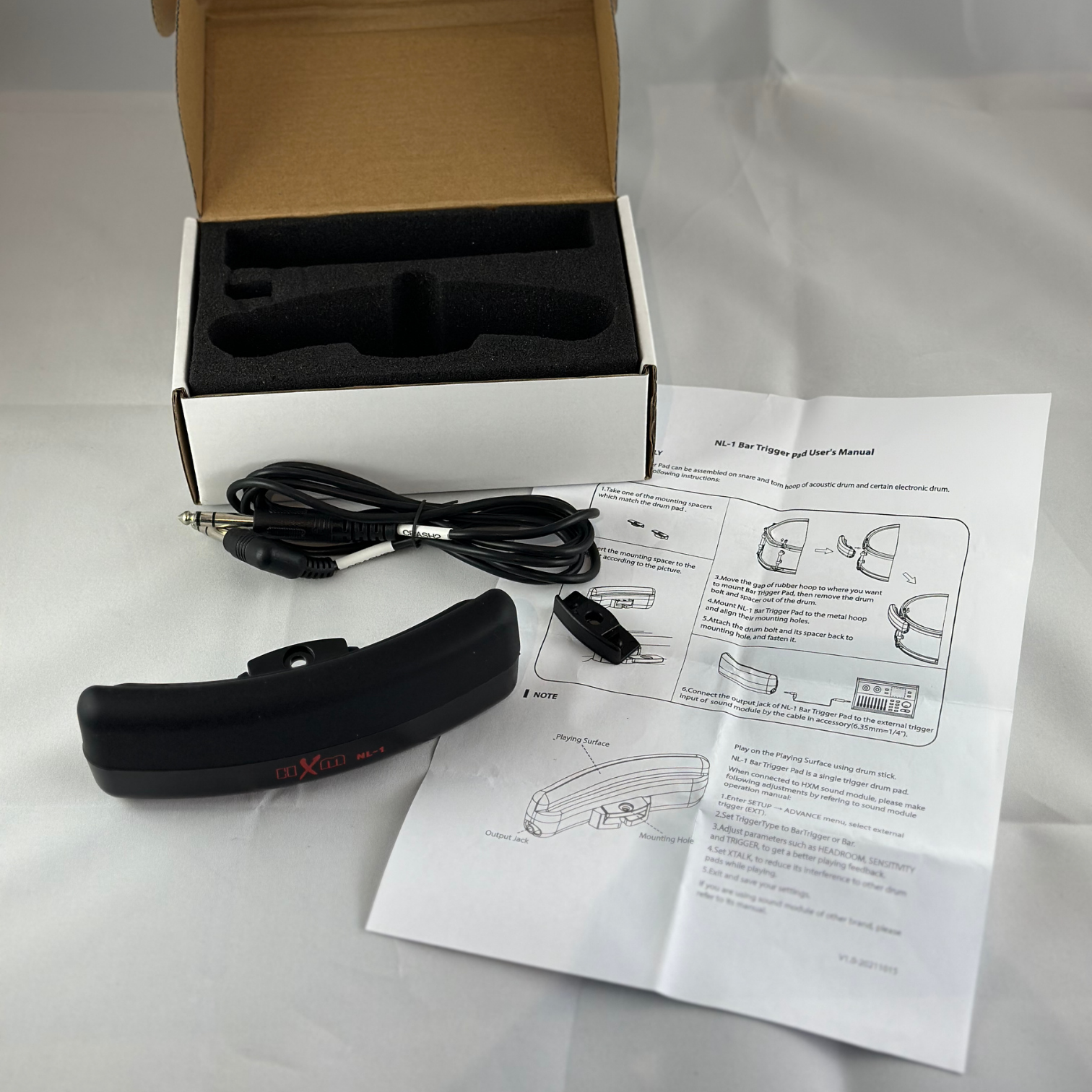 HXM Bar-trigger NL-1 with cable, mounting clip, user manual, and open box on white background