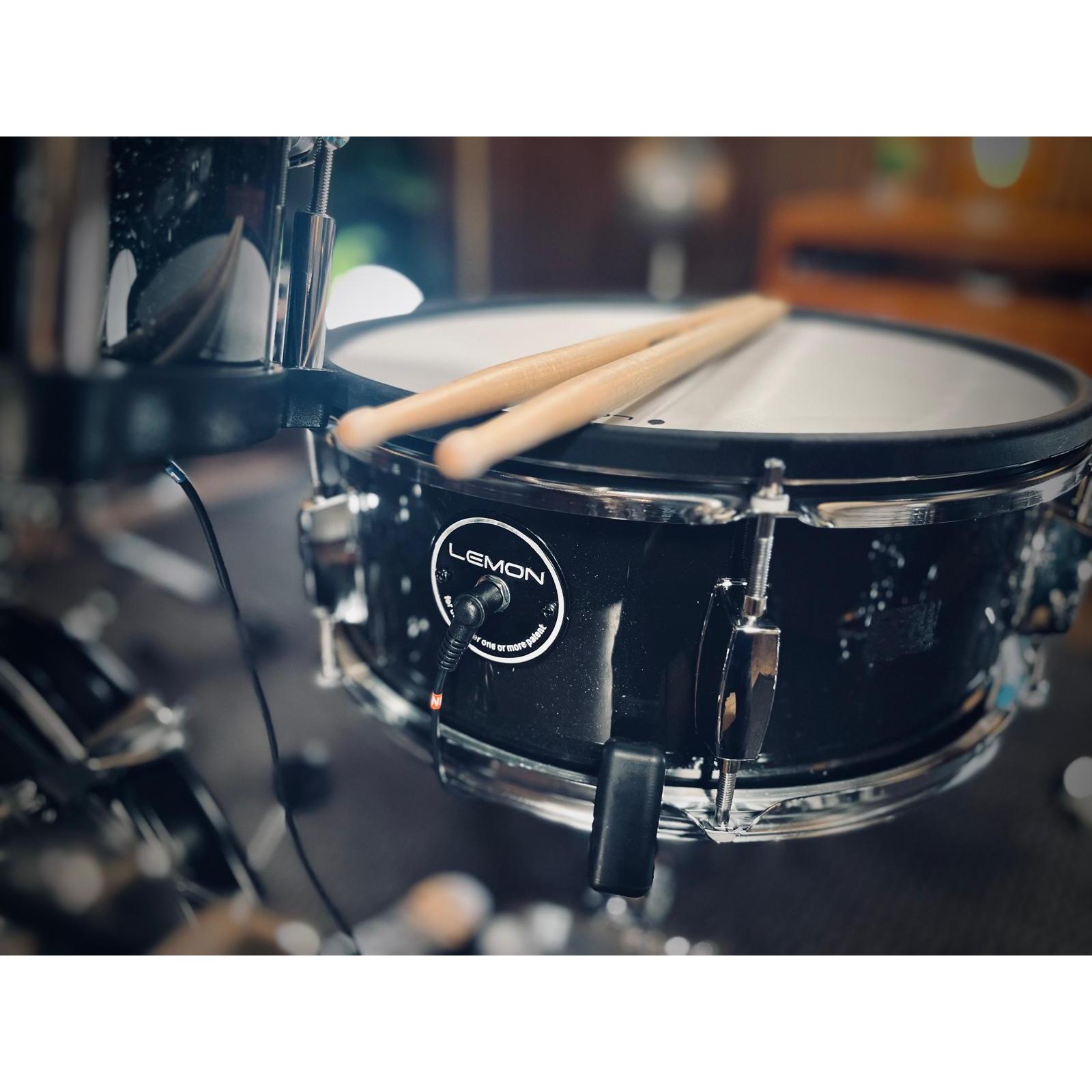 Close-up of a black sparkling snare drum with sticks on top from the Jack Lemon drum kit by Lemon.