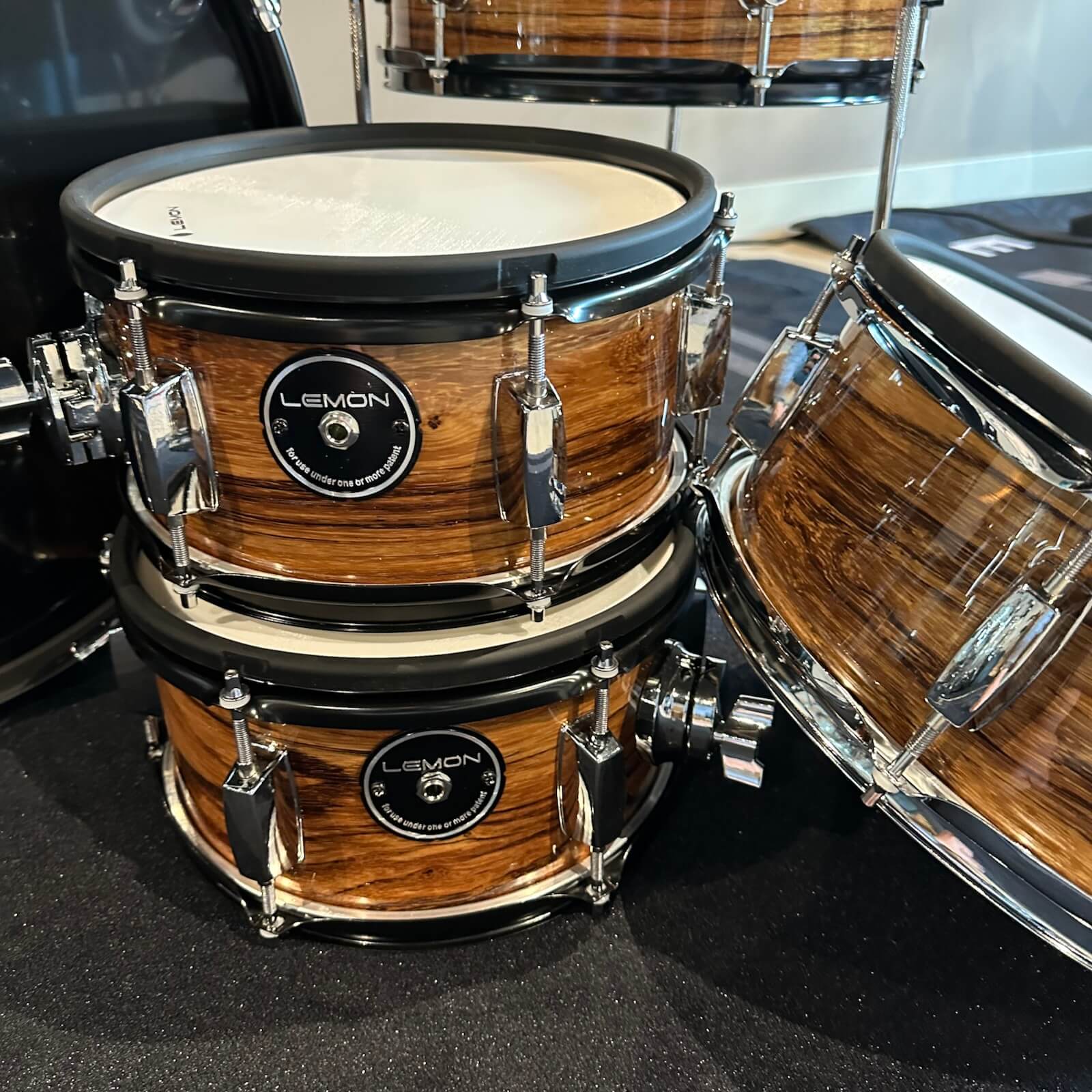 Close-up of Lemon Dark Wood Grain rock e-drum shell set showing real wood shells with dark brown finish and hardware