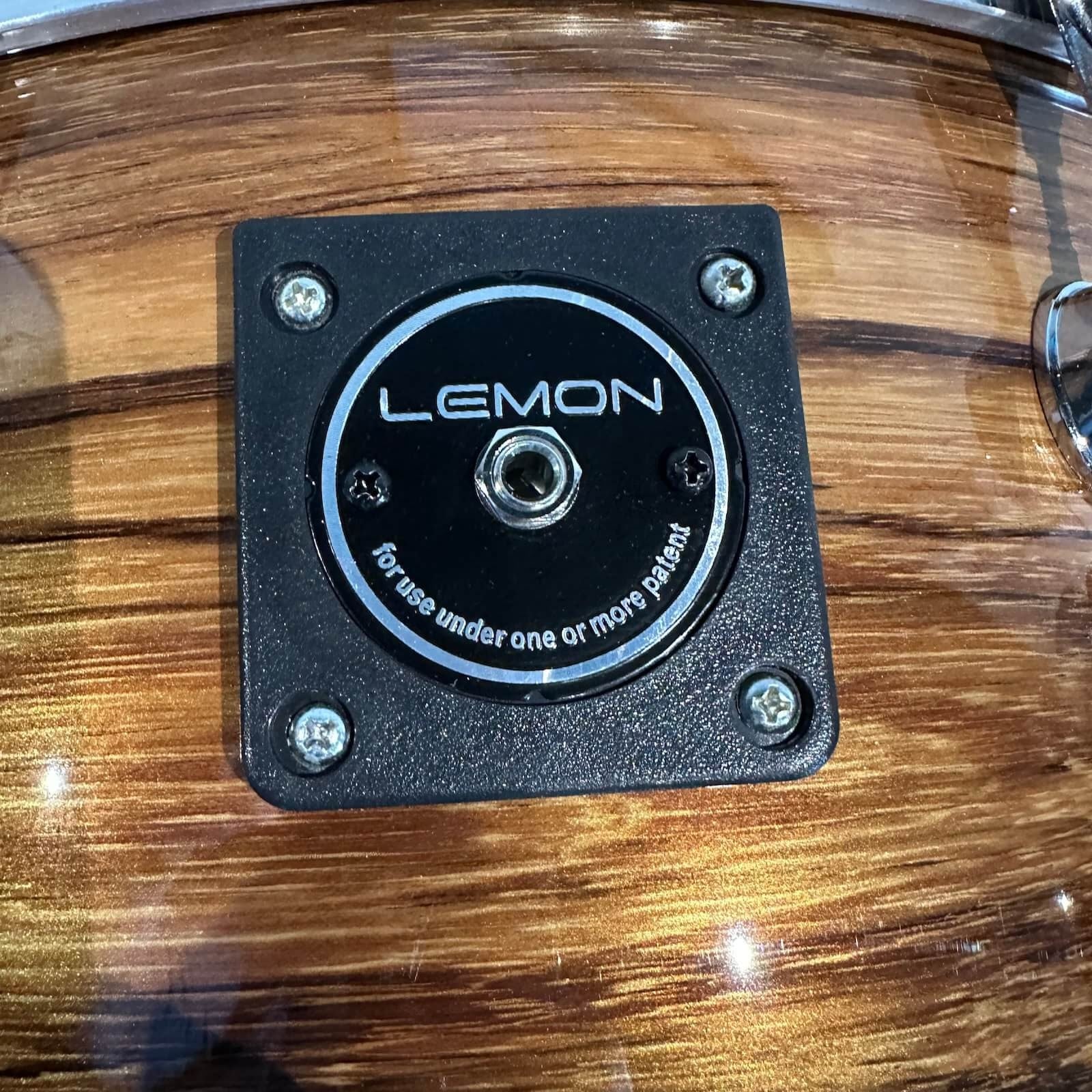 Close-up of wood shell binding plate on Lemon Dark Wood Grain rock e-drum shell set showcasing dark brown finish and metal hardware