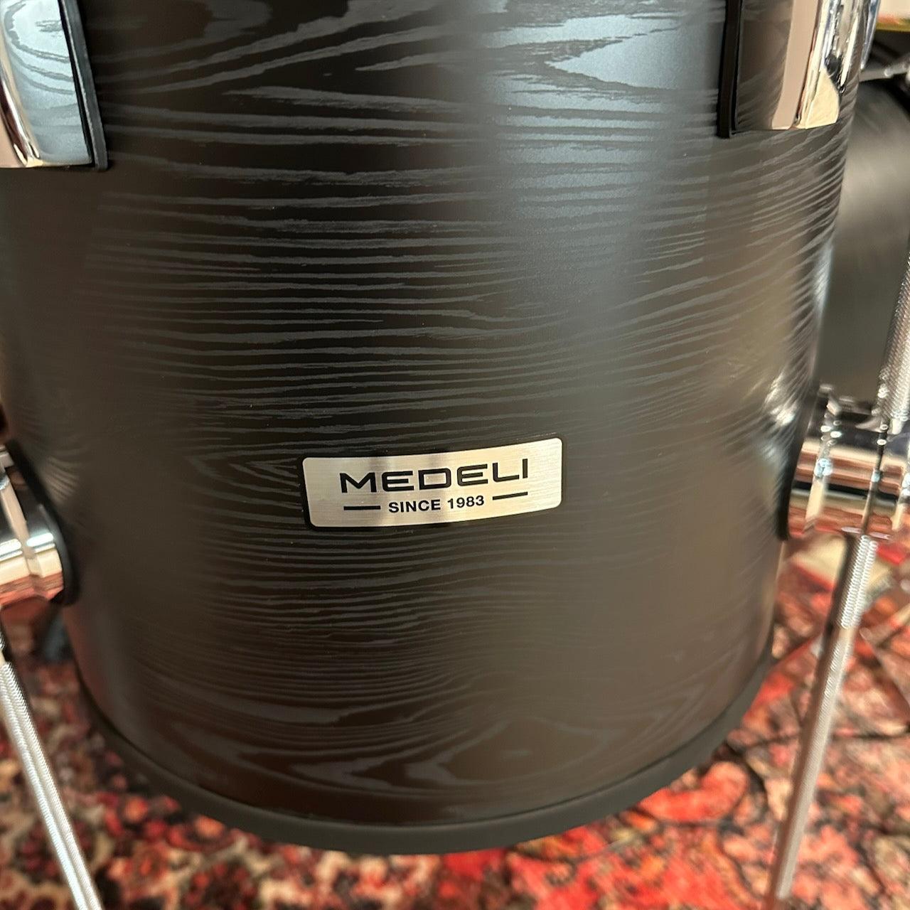 Close-up of the black woodgrain shell on the Medeli MZ729 digital drum kit highlighting the metal MEDELI badge