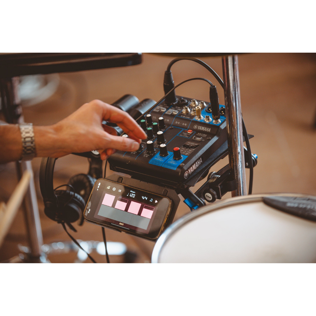 Hand adjusting audio mixer placed on NBO Angled Extension for Oneboard with connected device and headphones nearby