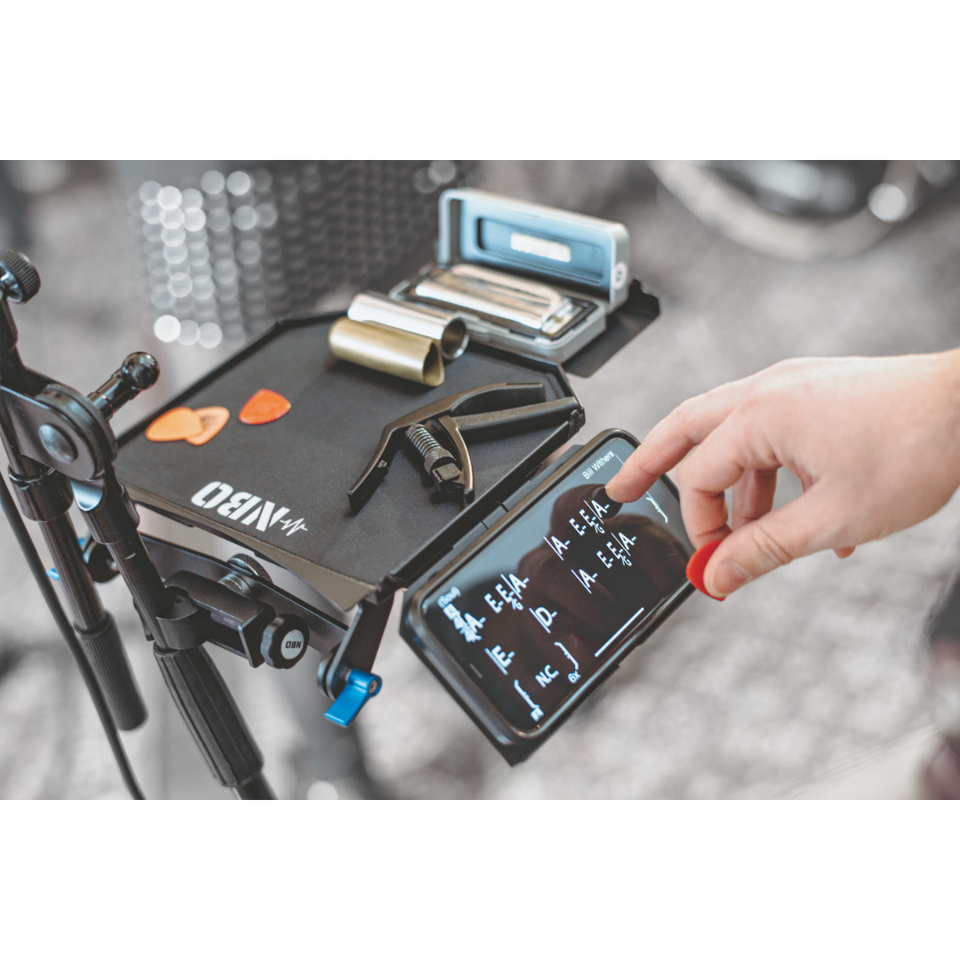 NBO Angled Extension for Oneboard showing black surface with guitar picks and a phone held at ergonomic angle by a hand