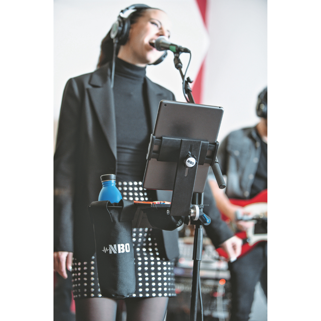 NBO Tablet/Phone Holder for Oneboard attached to microphone stand holding a tablet and bottle with a singer in background