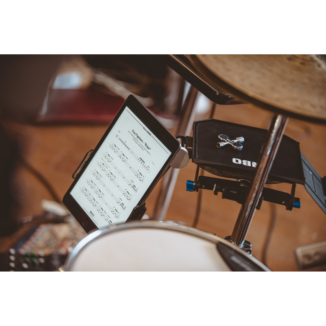 NBO Tablet/Phone Holder for Oneboard holding a tablet with sheet music near a drum set with steel rotative arm in focus