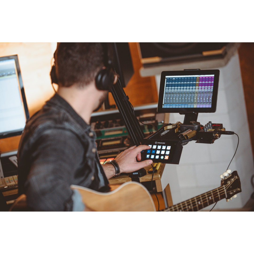Musician using NBO Tablet/Phone Holder for Oneboard with mixing software in a recording studio setup.