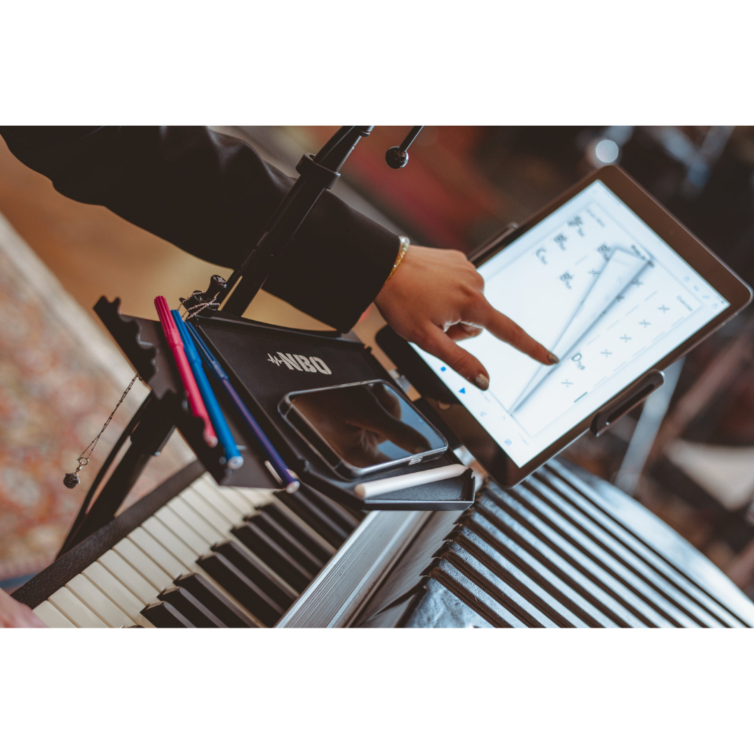 NBO Tablet/Phone Holder for Oneboard attached to music stand holding tablet and phone with pencils nearby