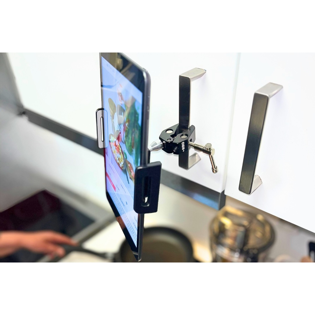 NBO Universal Tablet/Phone Holder clamped on kitchen cabinet handle holding a tablet in use above a stove.