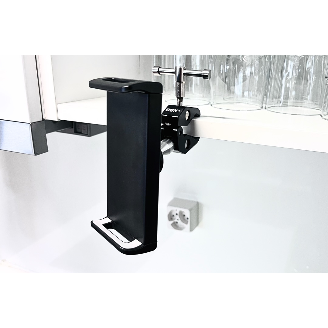 NBO Universal Tablet/Phone Holder mounted on a clamp under a kitchen shelf, designed for secure versatile use.