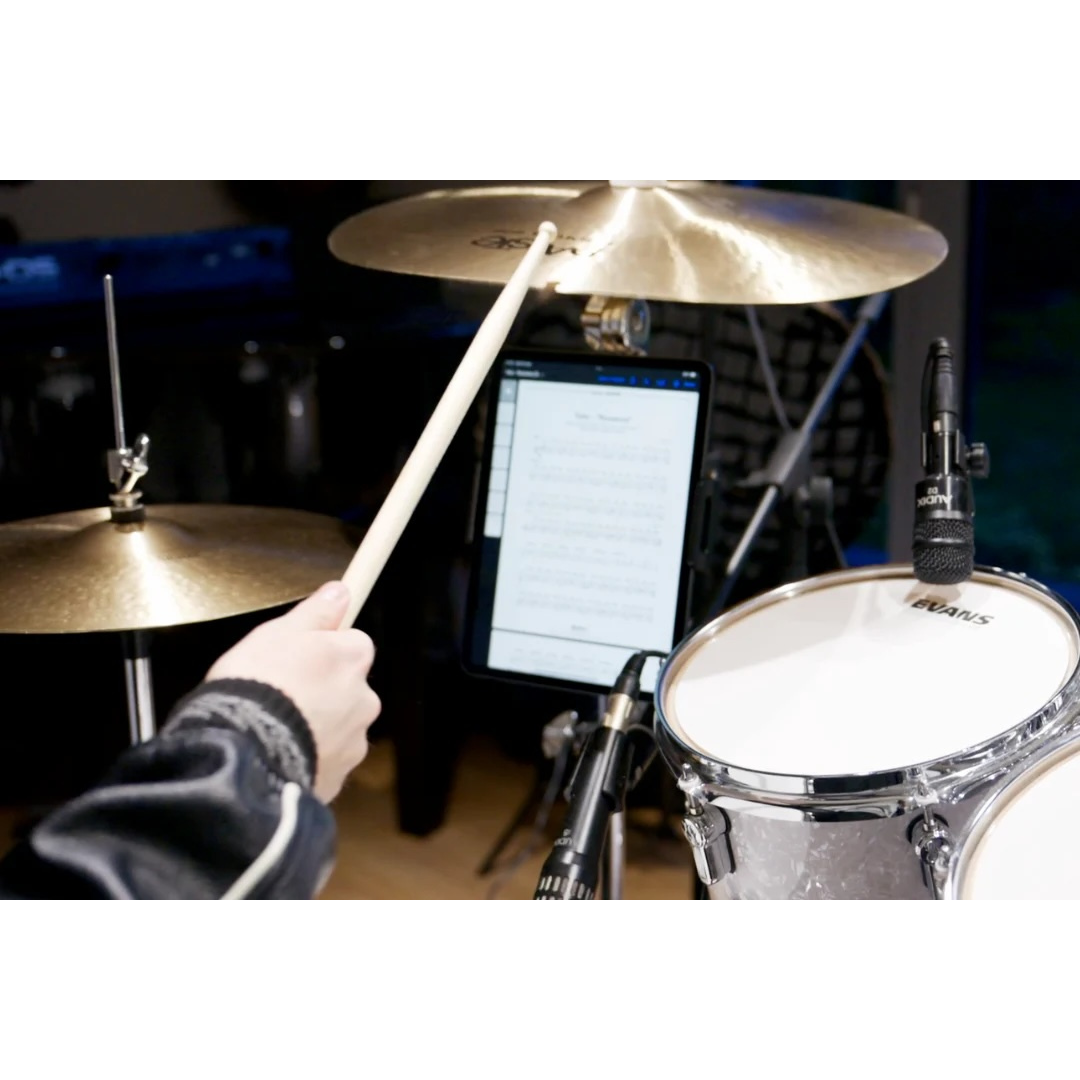 NBO Universal Tablet/Phone Holder mounted on drum set holding a tablet with sheet music visible for musicians.