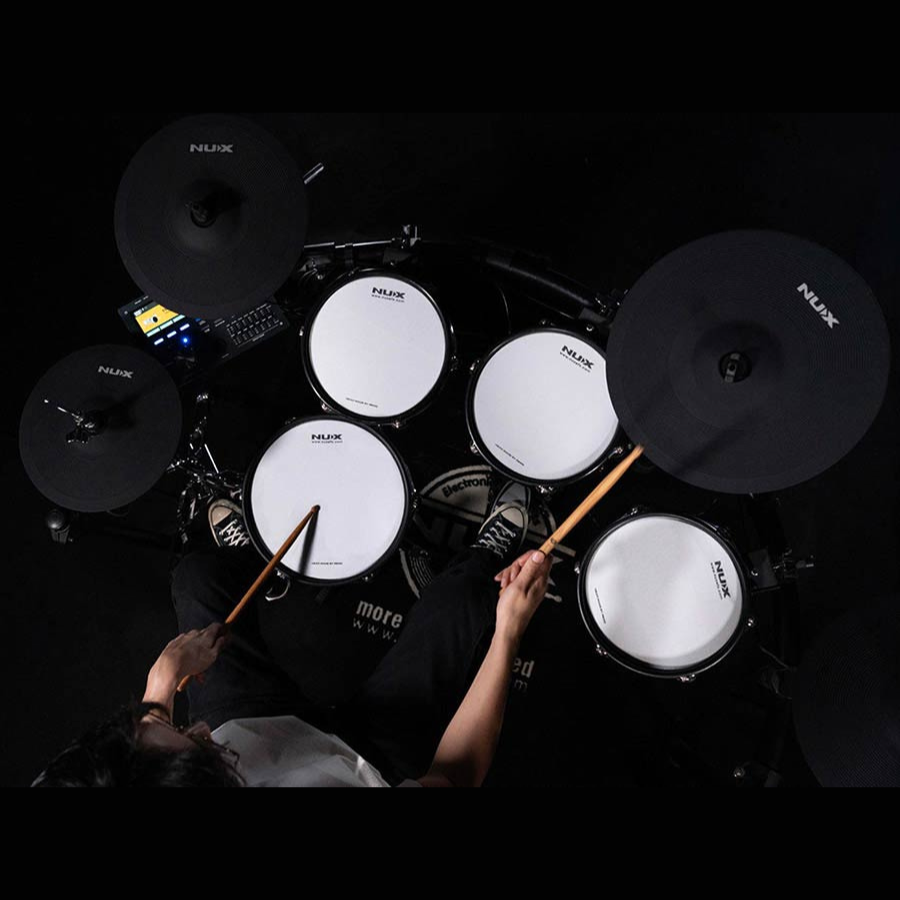 Top view of a person playing the NUX DM-8 Flagship Digital Drum Kit with drumsticks on black pads and cymbals.