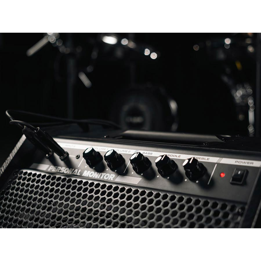 Close-up of NUX NPA-100 Professional Monitor Speaker 120W control panel with volume and tone knobs in dark setting
