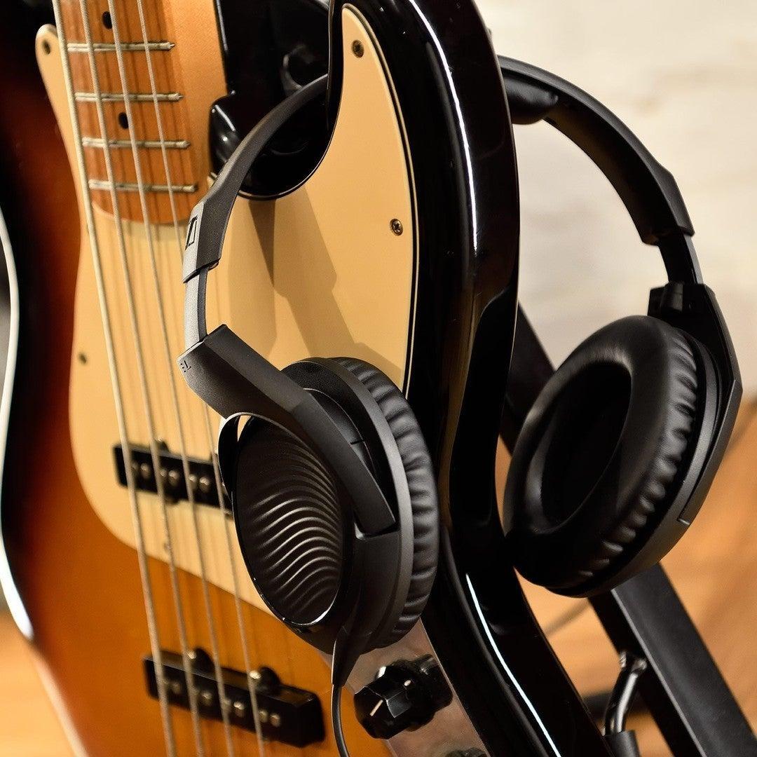 Sennheiser HD 200 PRO Monitoring Headphones hanging on the body of a black and beige electric bass guitar